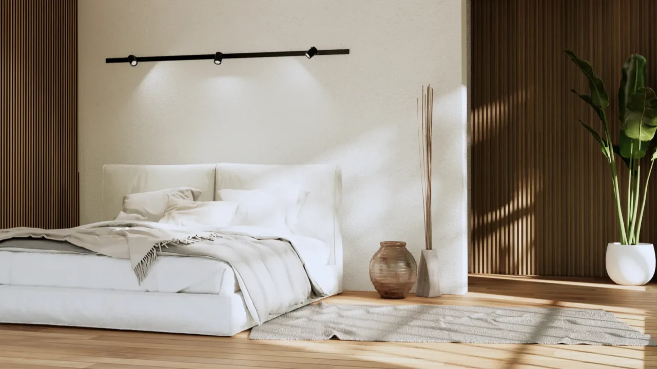 A minimalist bedroom interior with flannel bedding, rug, and potted plant.