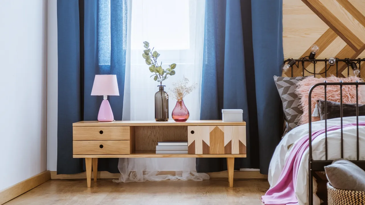 Pastel bedroom interior with blue curtains and pink lamp and vases.