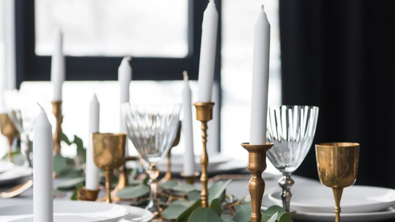 rustic table arrangement with eucalyptus, vintage cutlery, candles in candle holders and empty plates