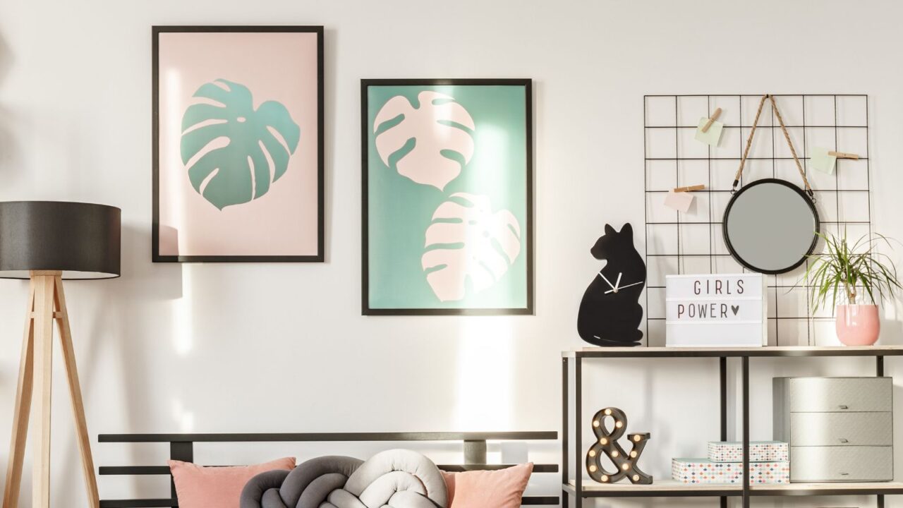 A modern living room interior with a floor lamp, shelves with decor like '&' sign, cat clock, and a planter and botanical posters on wall.