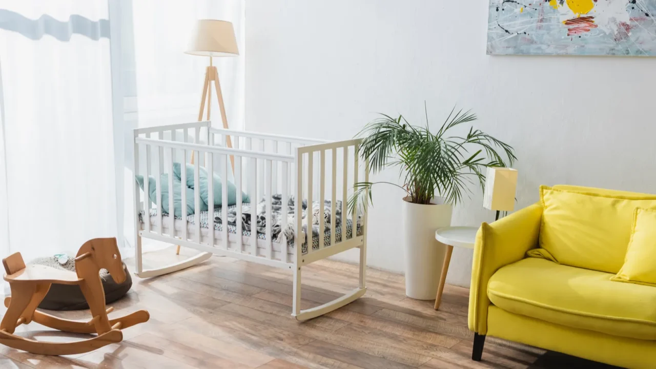 spacious room with yellow sofa, baby crib and rocking horse