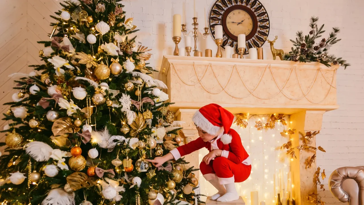 the little boy to Santa's red suit decorates a Christmas tree