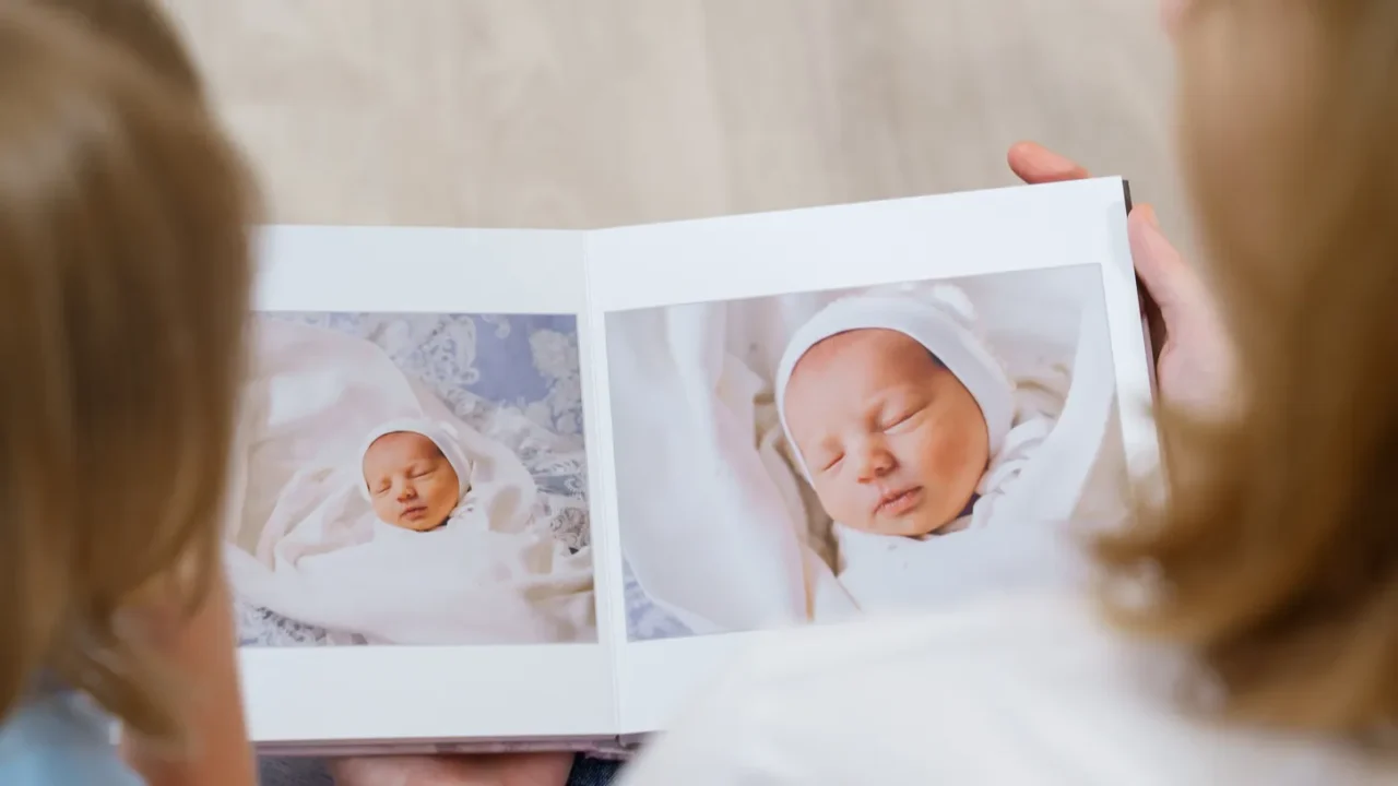 top view. mother and daughter watch photobook from discharge of newborn baby