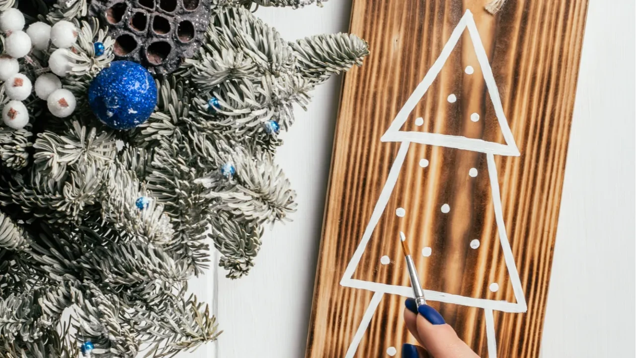 womans hand draws christmas tree on decorative board made of