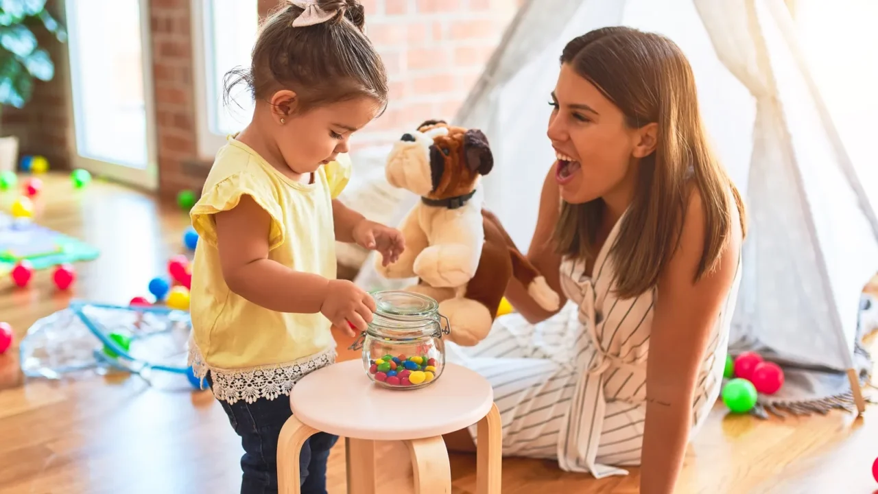 young beautiful teacher playing with dog doll and toddler holding