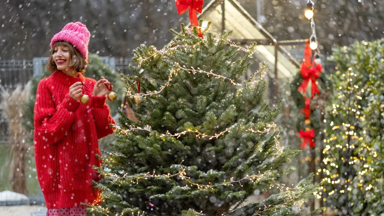 young woman in red decorates lush christmas tree with festive