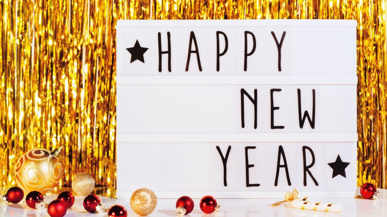 Happy New Year displayed on a lightbox with golden tinsel decoration in the background.