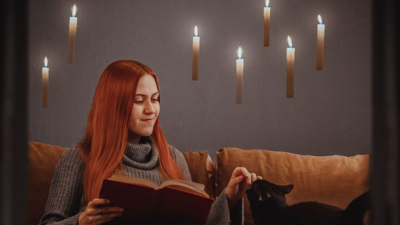 Girl reading a book with candles flying around