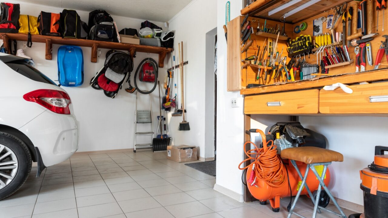 A well-organized garage with a car, tools, and storage shelves.