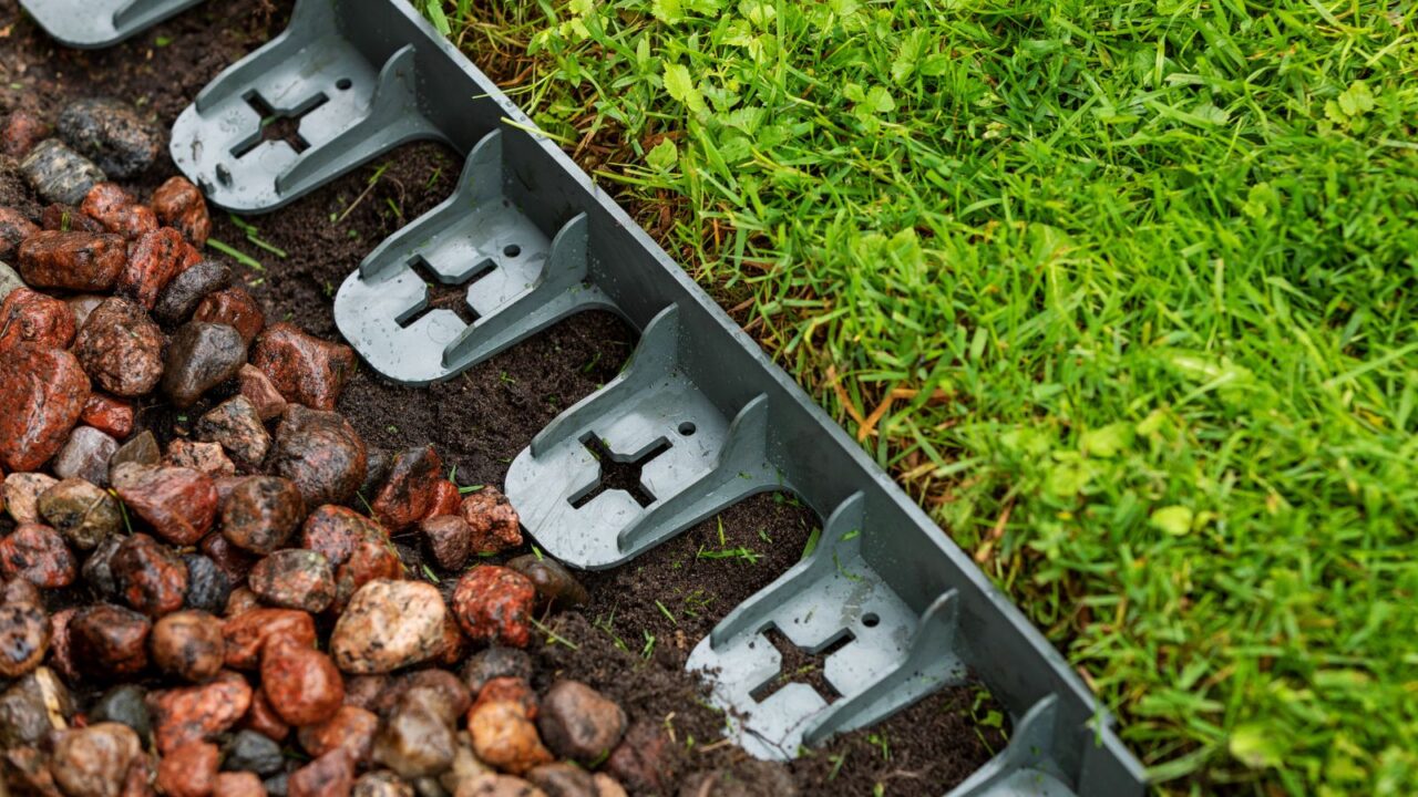 A plastic lawn edging in a yard separating grass and rocks.