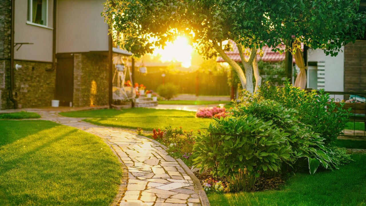 A beautiful yard with shrubs, trees, flowers, and a gravel pathway.