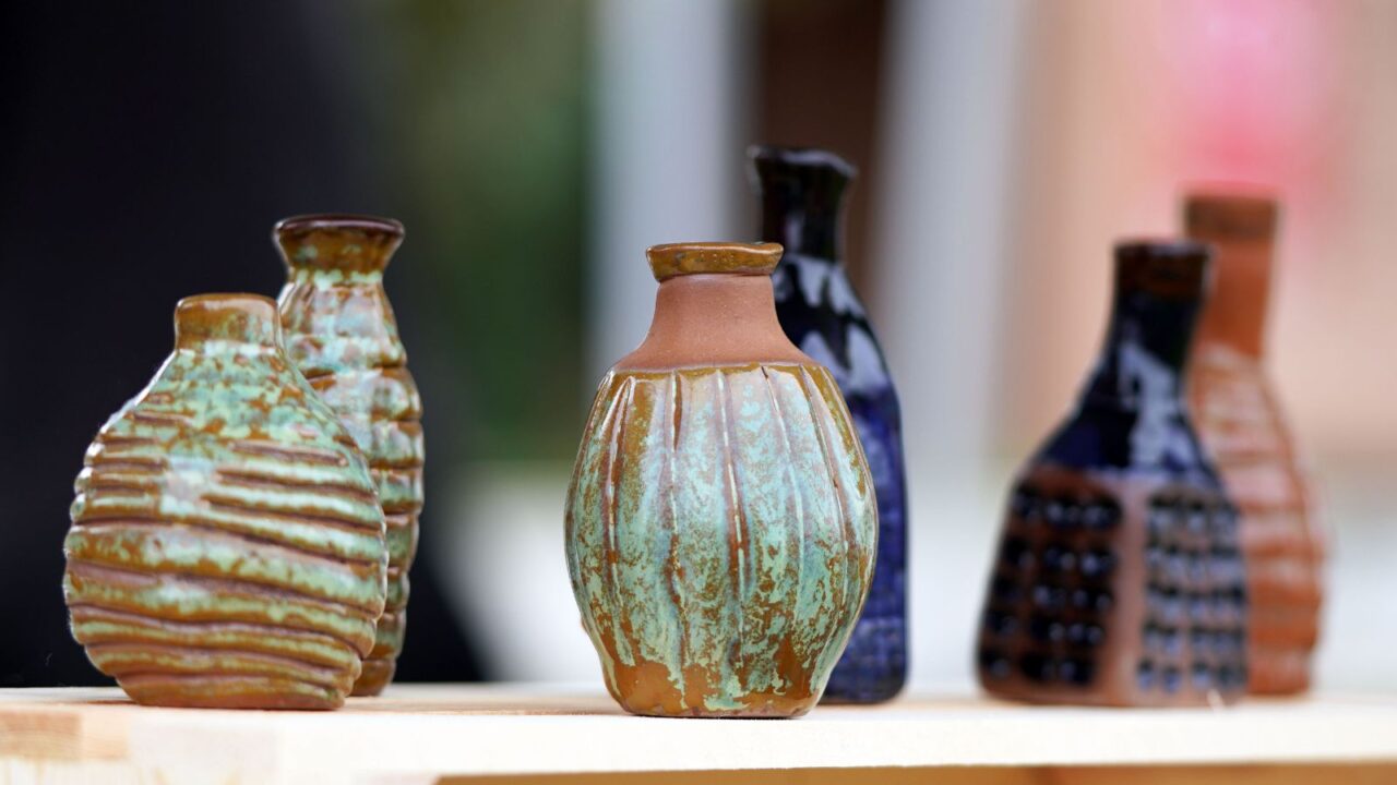 Beautiful handmade pottery pots in different colors placed on a wooden table/