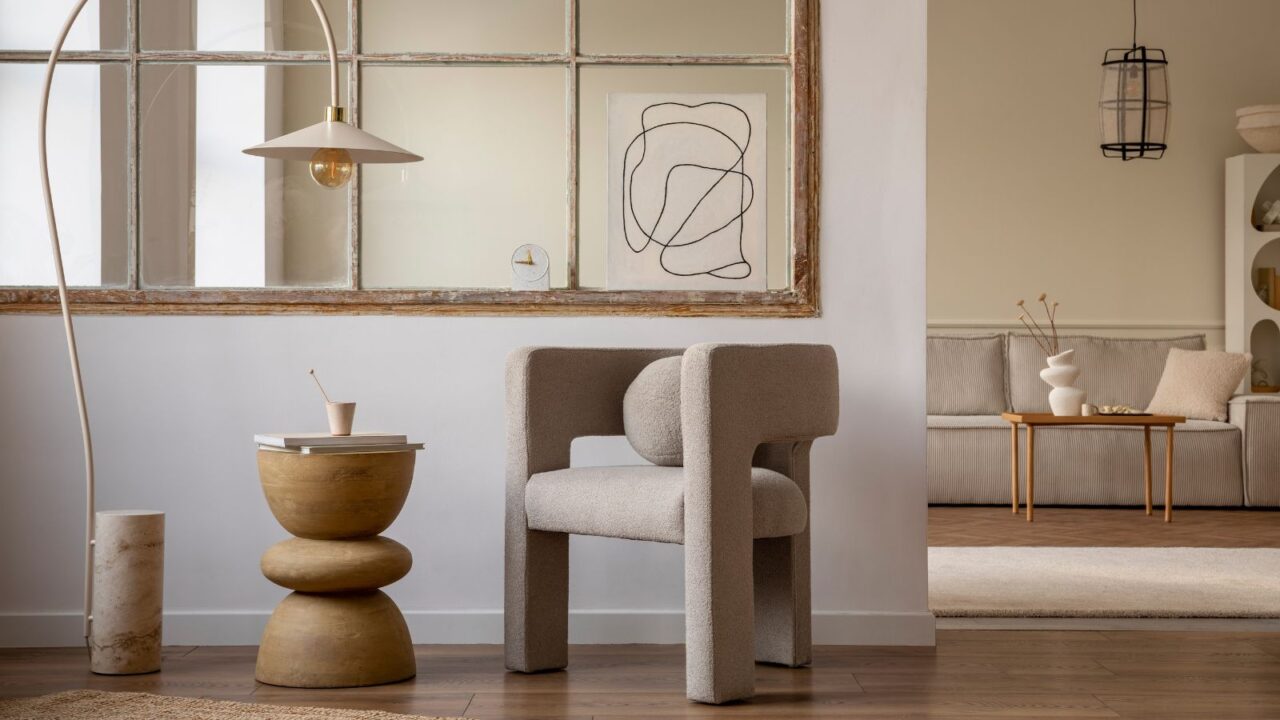 A living room interior with a lamp, boucle chair, coffee table, and a poster.