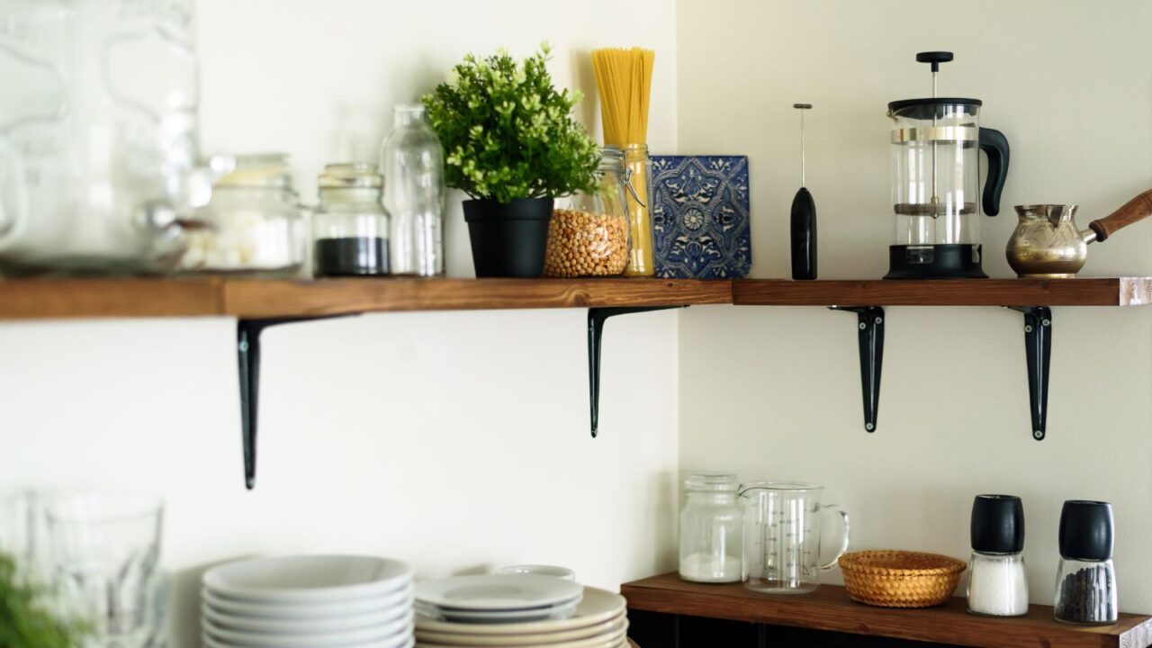 A wooden floating shelf with plant pot, plates and jars.