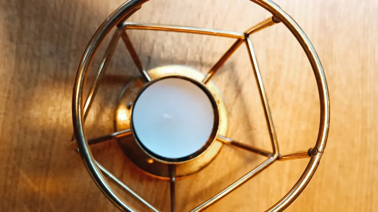 a candle in a metal candle holder on a wooden