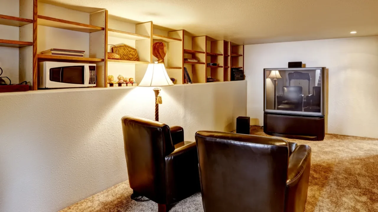 basement room with tv and two leather chairs