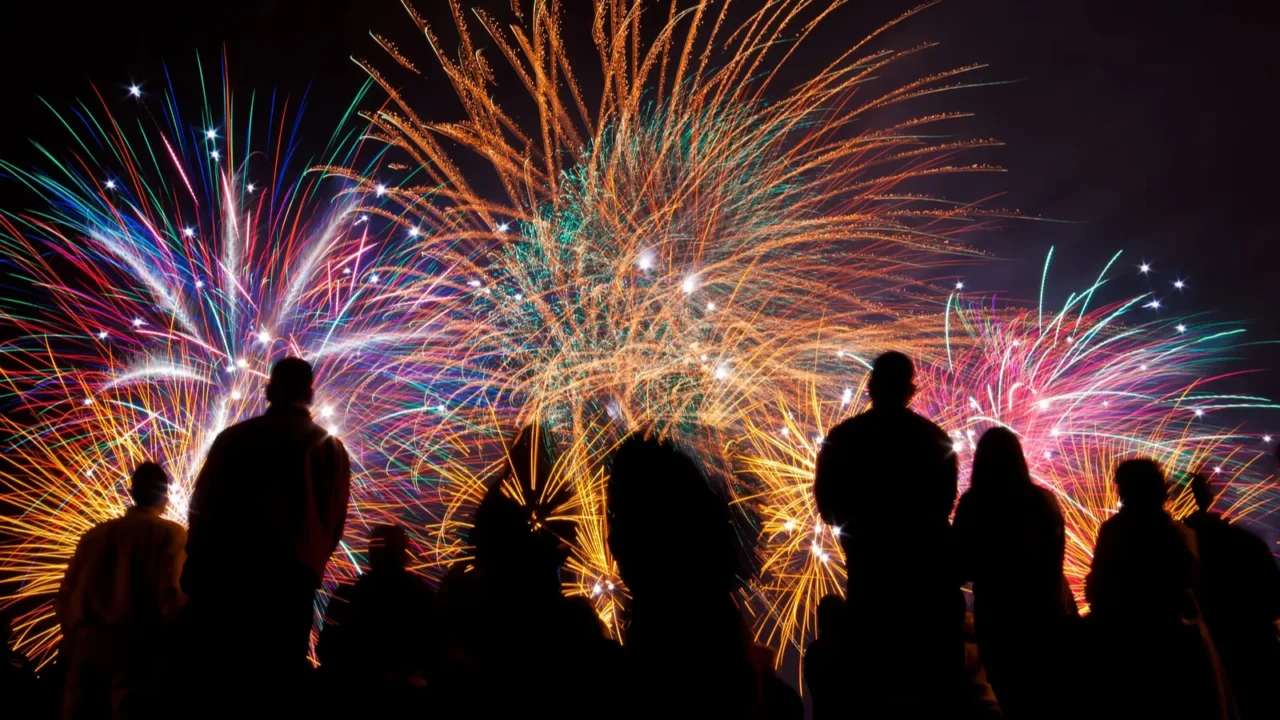 big fireworks with silhouettes of people watching it