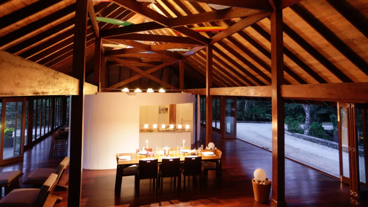 Big room with a dining table in the middle and wooden beams