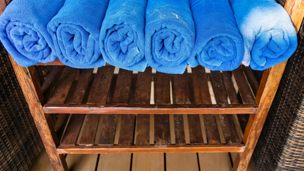 blue towels neatly rolled and arranged on a wooden shelf