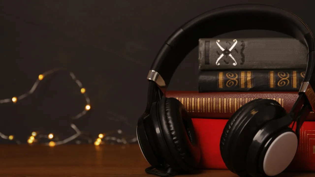 books and headphones on wooden table against black background s