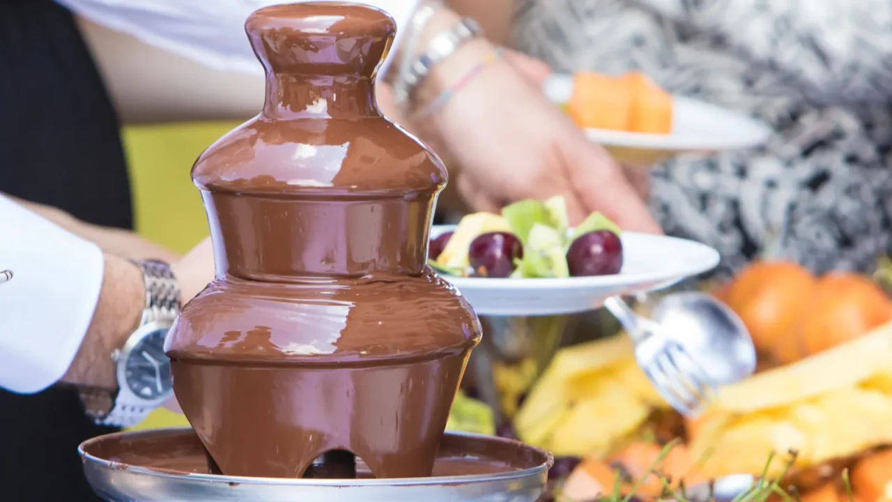 chocolate fountain at a party with waiters serving guests and