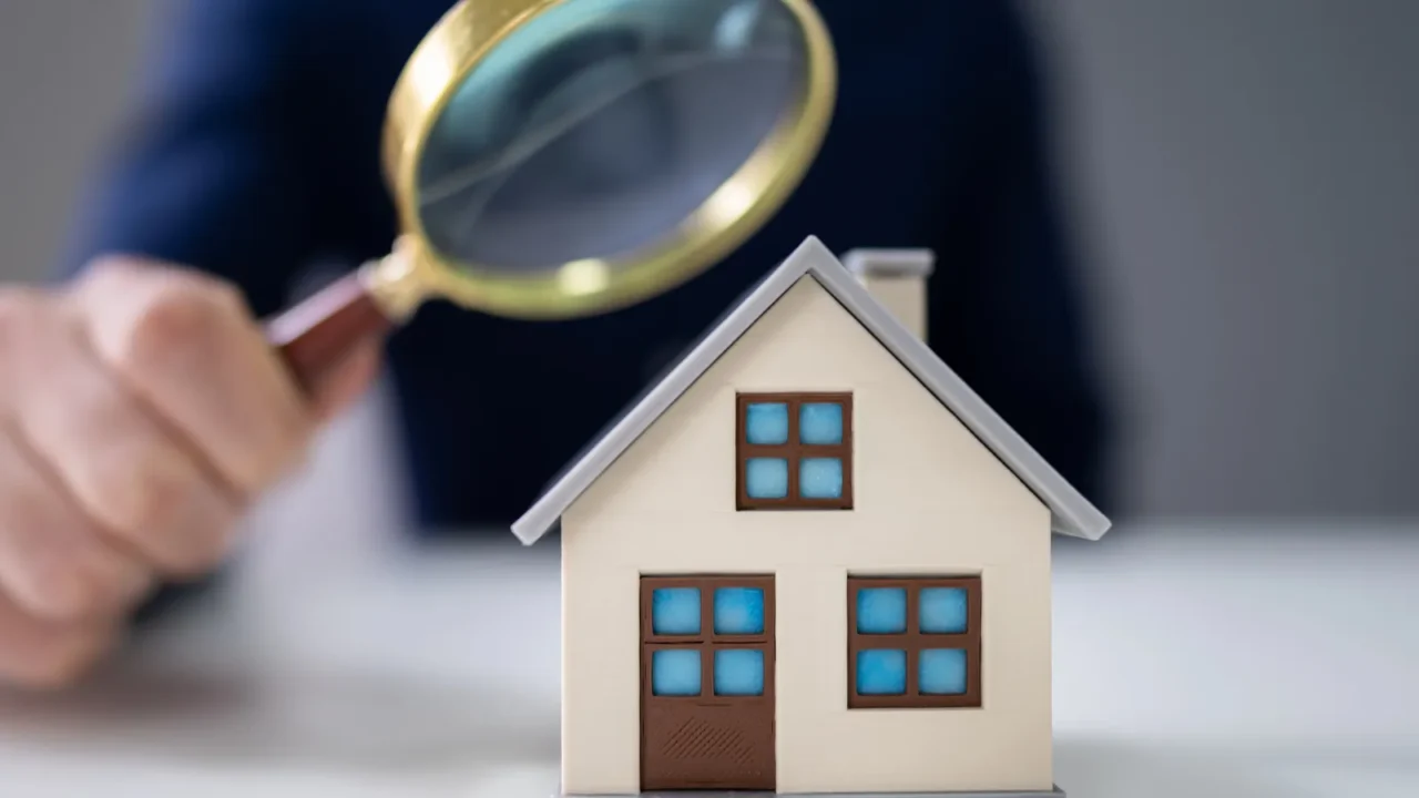 closeup of a businesspersons hand looking at house model through