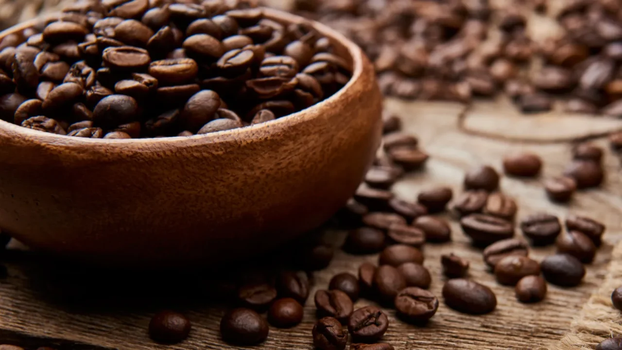 close up view of coffee beans on bowl on wooden