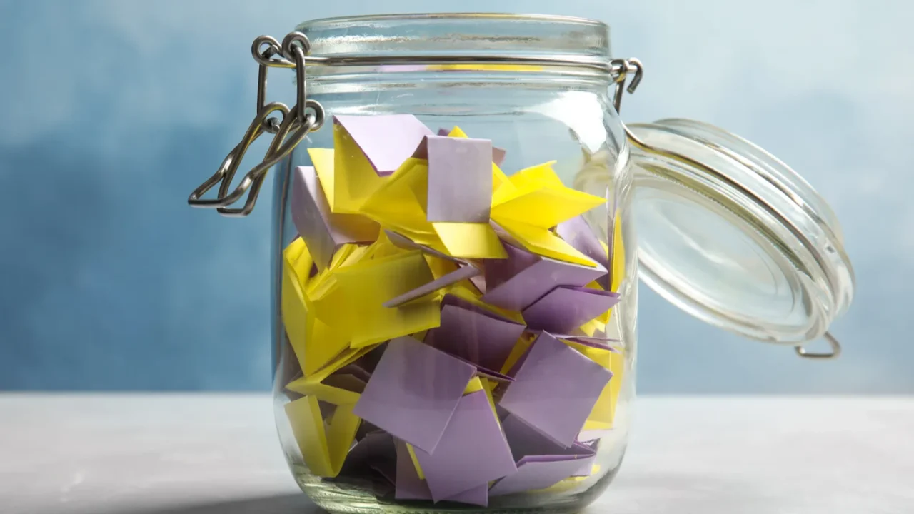 colorful paper pieces for lottery in glass jar on color