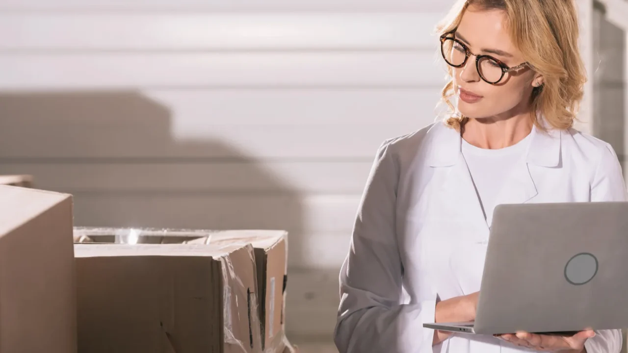 concentrated storekeeper using laptop while looking at cardboard boxes in