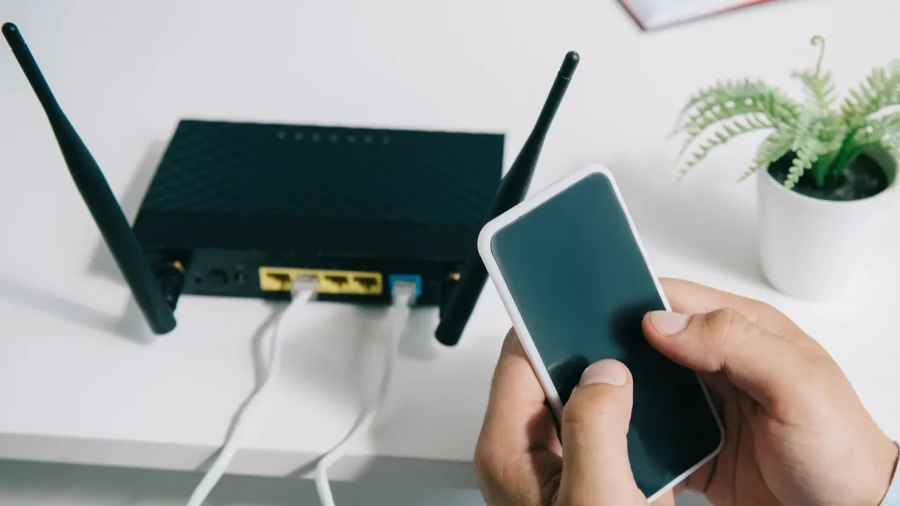 cropped view of businessman holding smartphone near plugged router