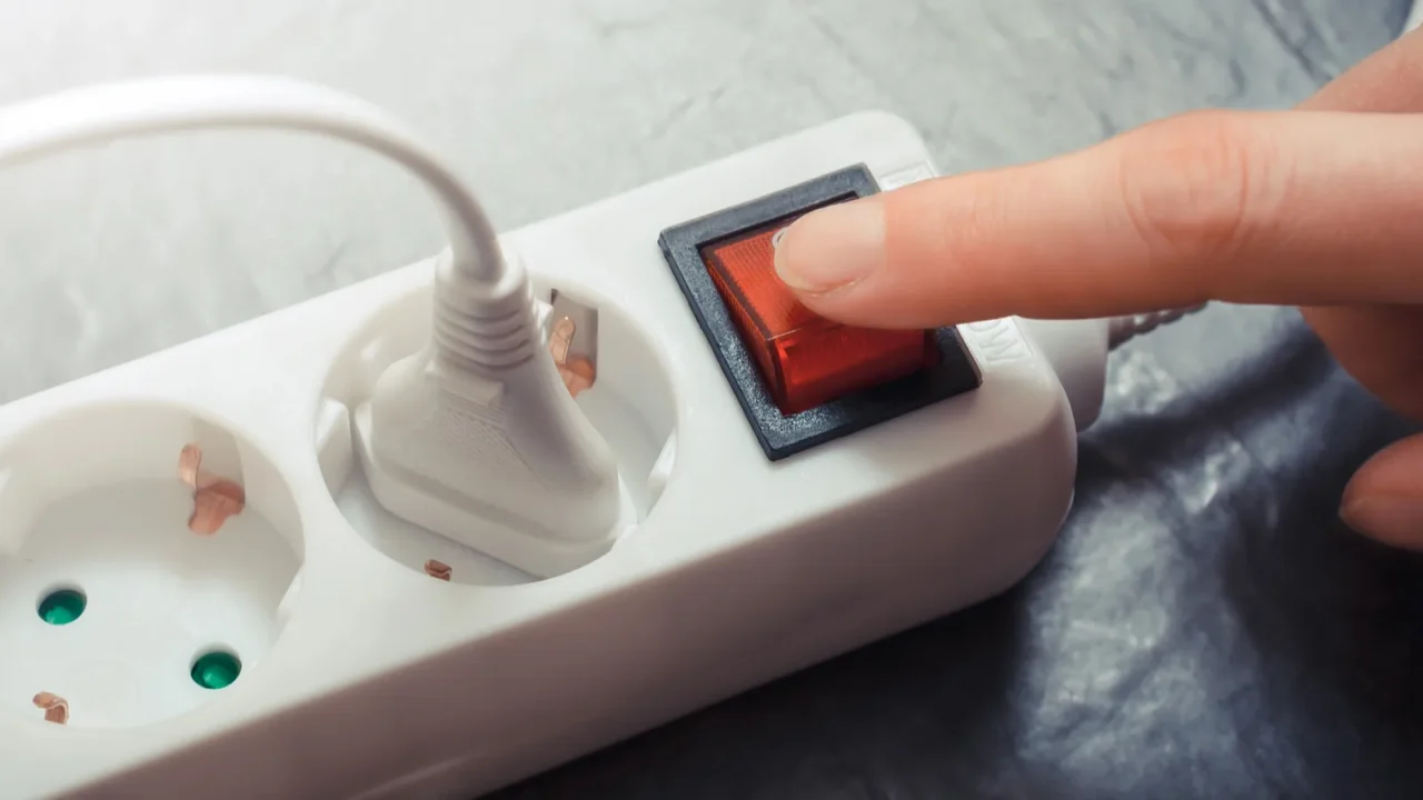 female hand pressing red switch of multiple socket outlet saving