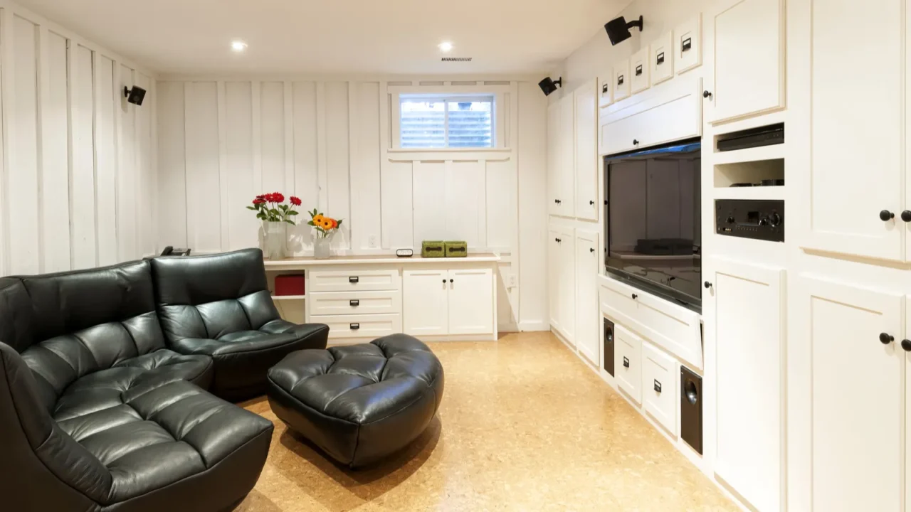 Furnished basement with black couch and a lot of cabinets for storage.