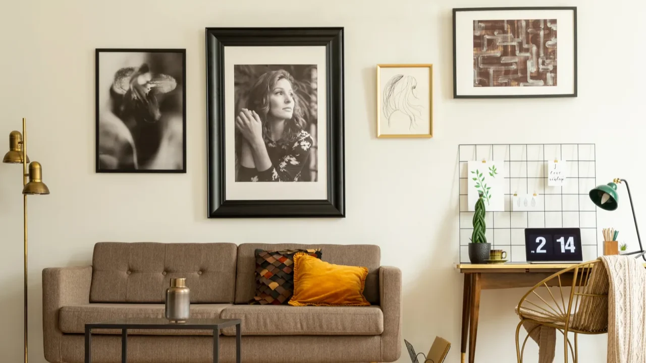 A living room interior with a sofa, coffee table, desk and chair, and gallery wall featuring art and photo frames.