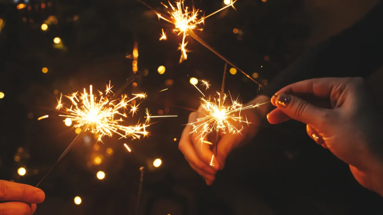 friends celebrating with burning sparklers in hands against christmas lights