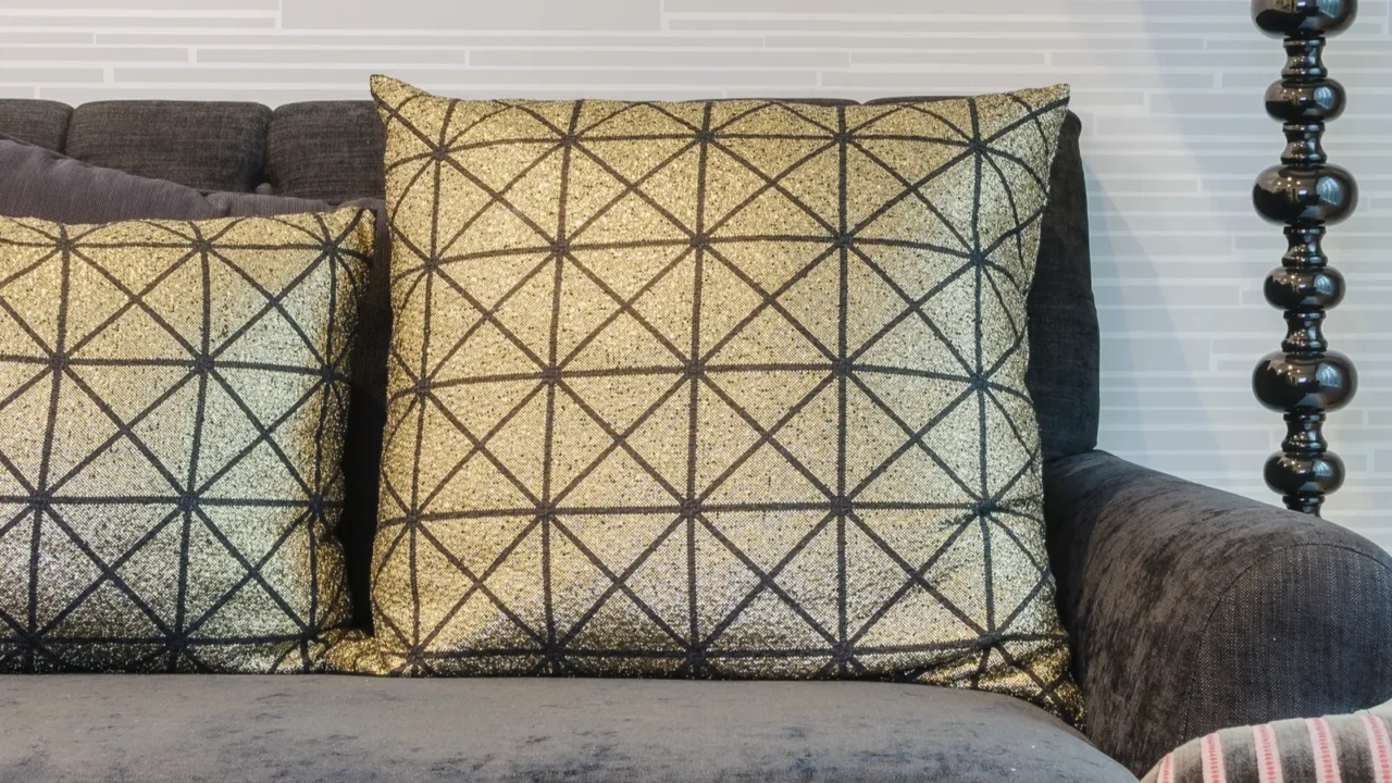 Gold pillows on black sofa in living room.