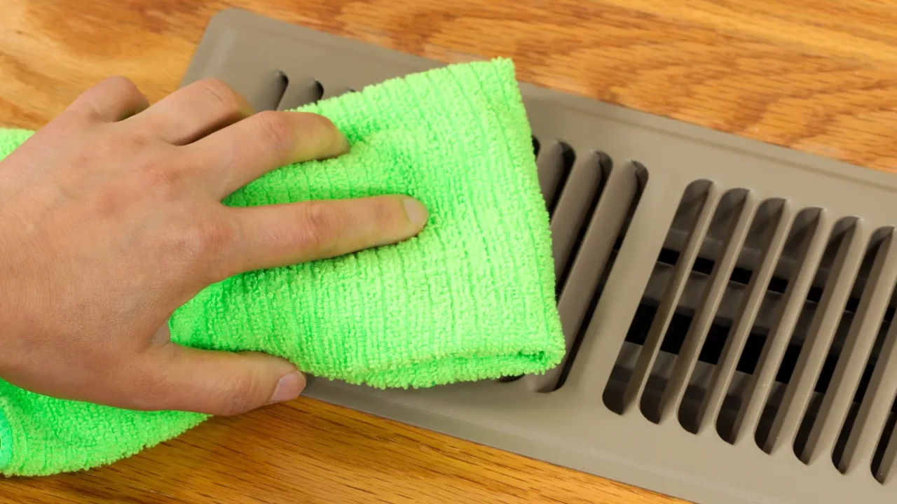 hand cleaning grill plate of floor heating vent in home