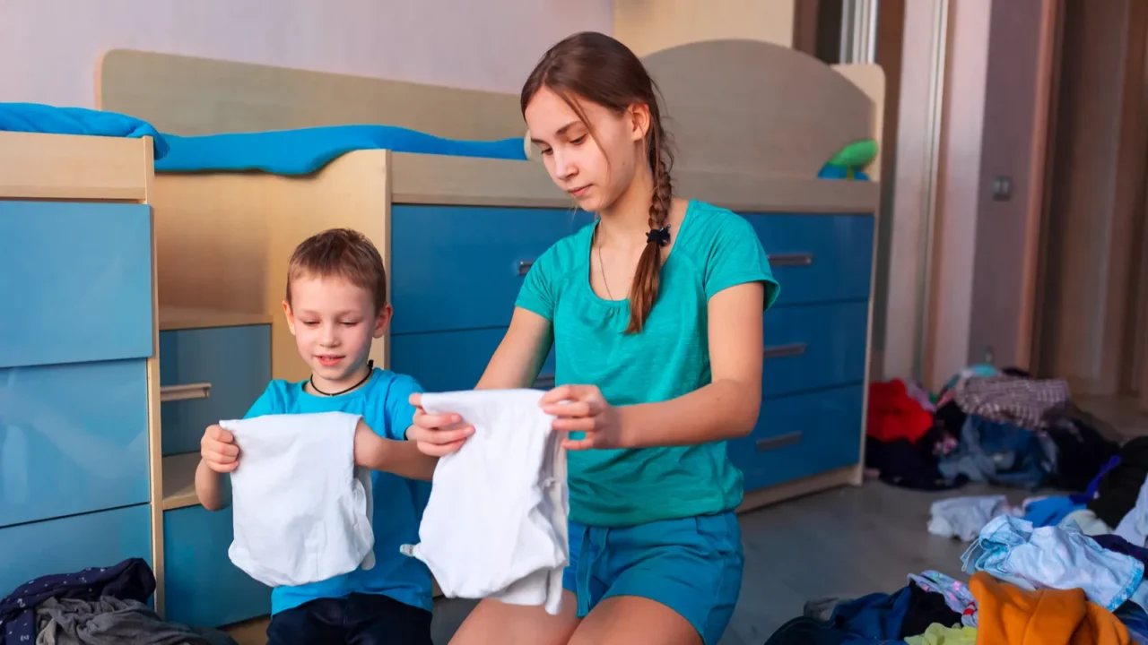 happy children folding clothes in thier messy bedroom