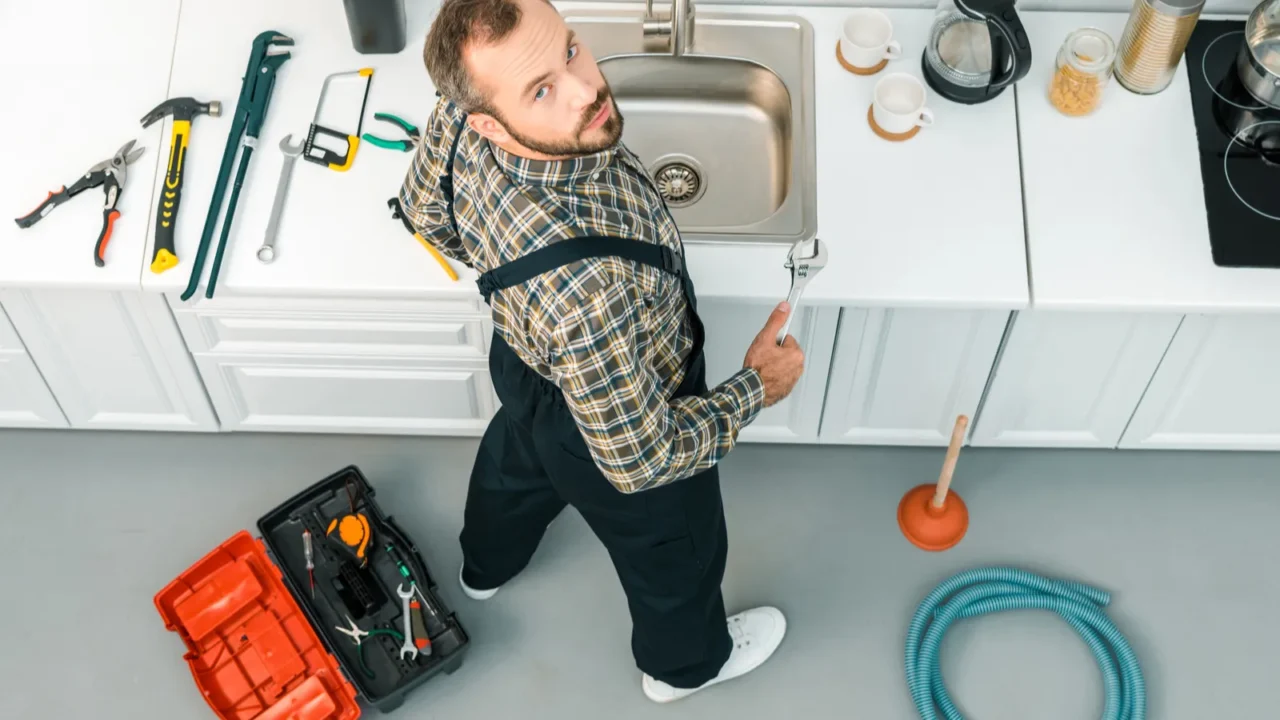 High angle view of handsome plumber holding adjustable wrench and