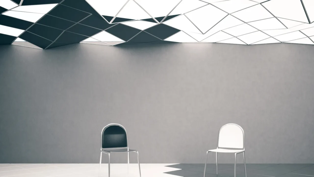 Two-toned black and white geometric ceiling. Black and white chairs on the floor.