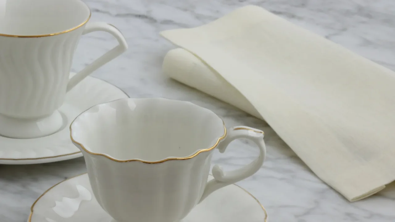 A lovely set of gold-rimmed tea cups with a French linen napkin.