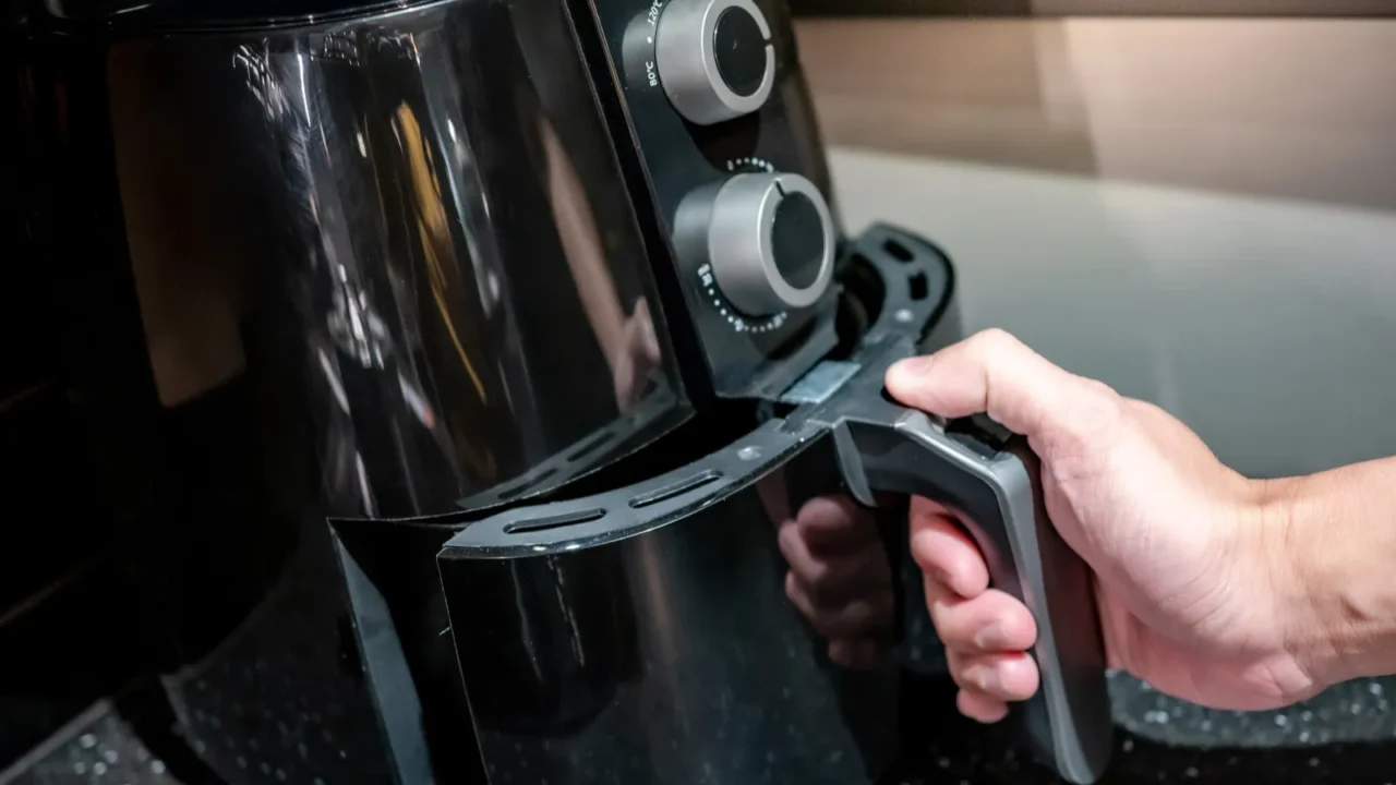 male hand holding an electric air fryer handle in the