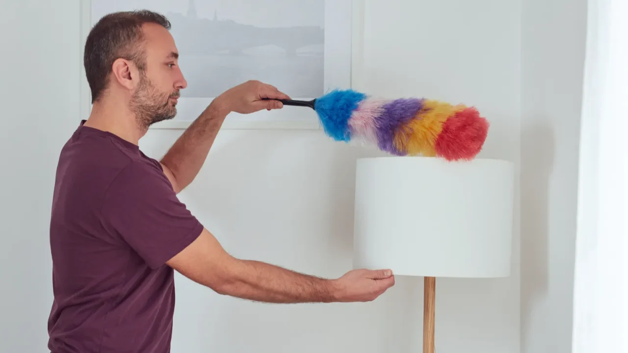 man cleaning apartment with dusting broom