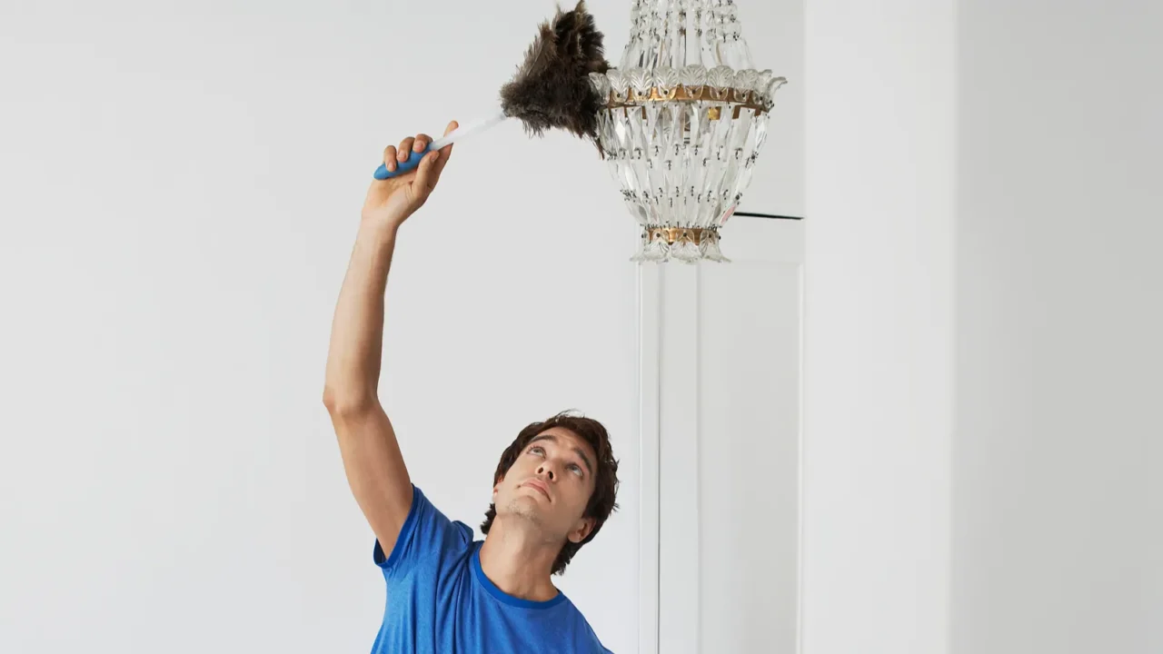 man dusting crystal chandelier