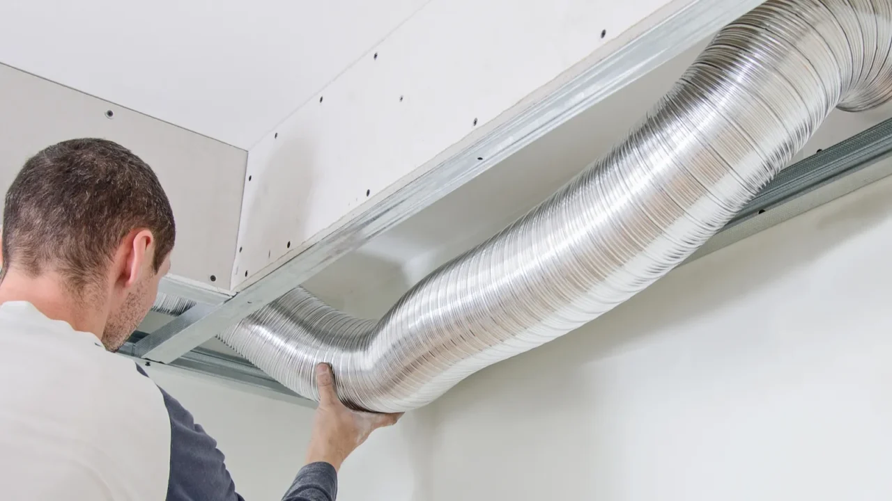 man setting up ventilation system indoors