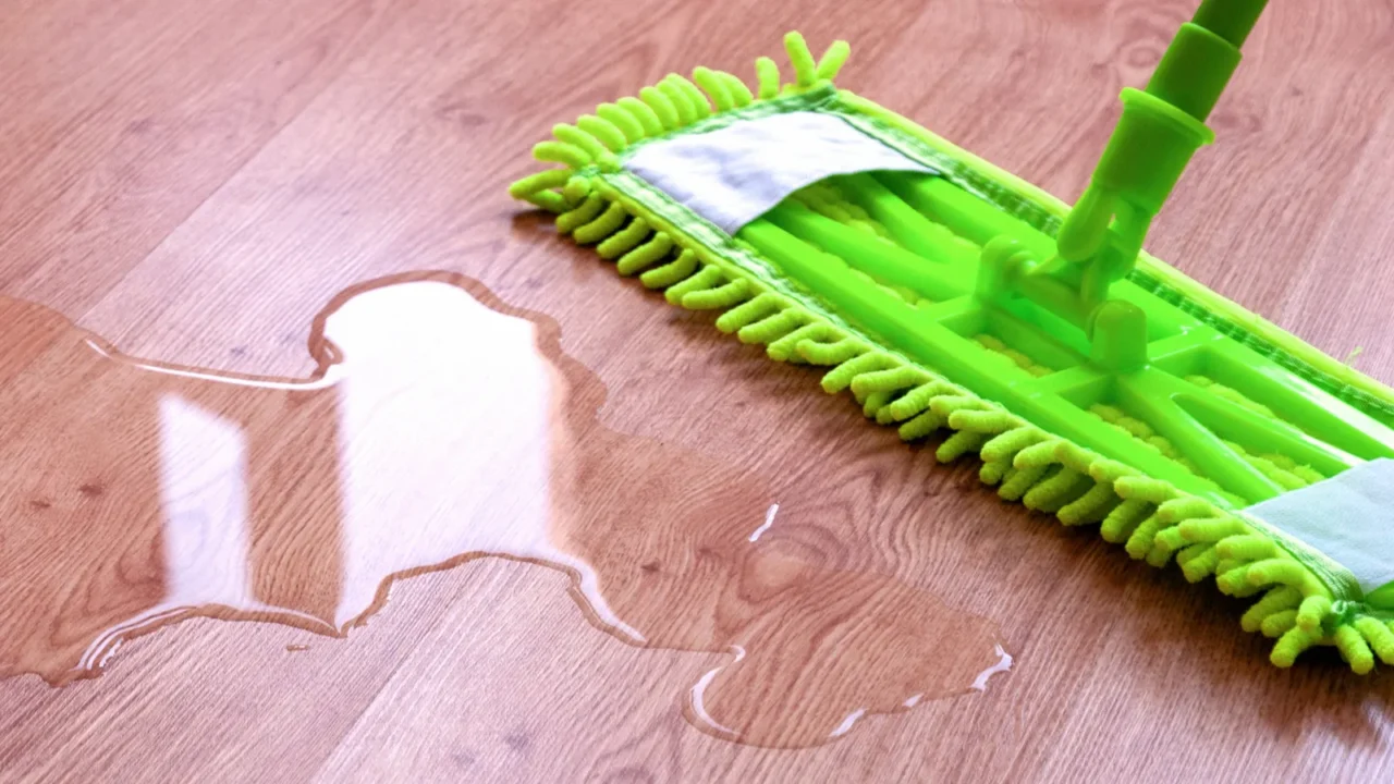 microfiber mop wiping puddle of water on laminate floor