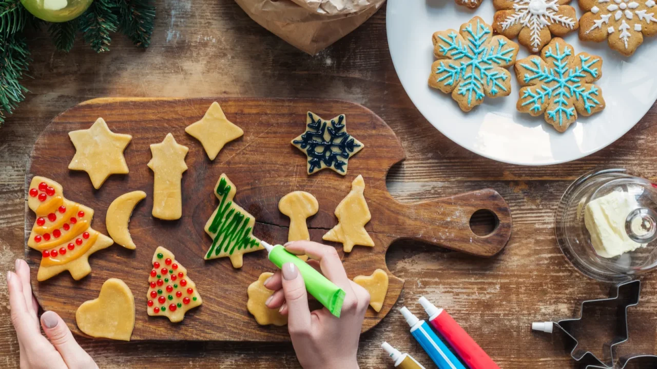 partial view of woman decorating homemade christmas cookies with food