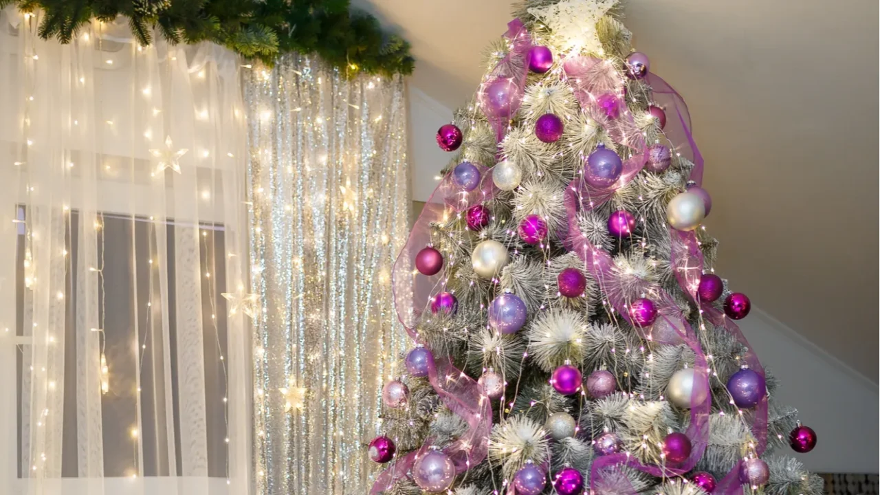 Pine tree decorated with purple bulbs shiny star and warm