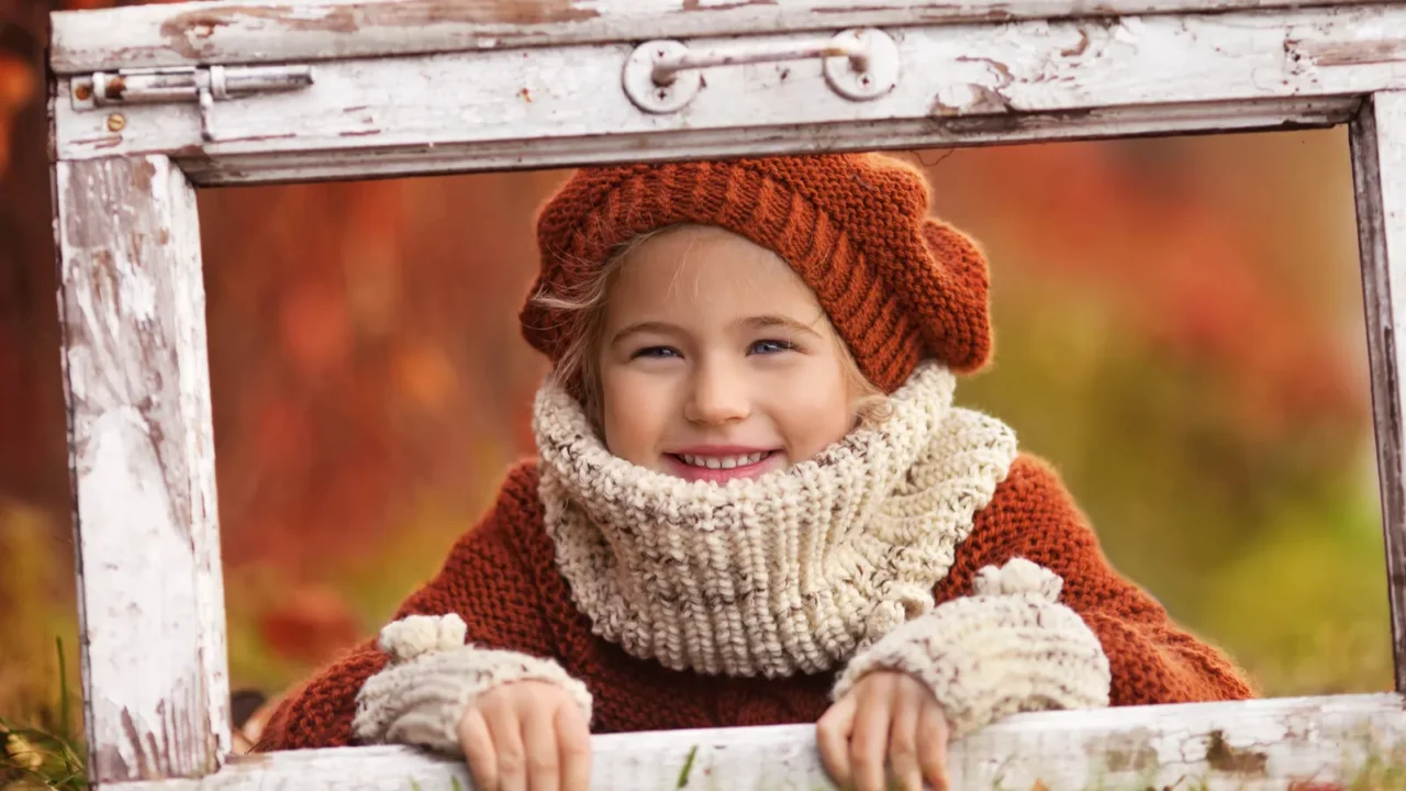 pretty little girl looks out of an old window frame