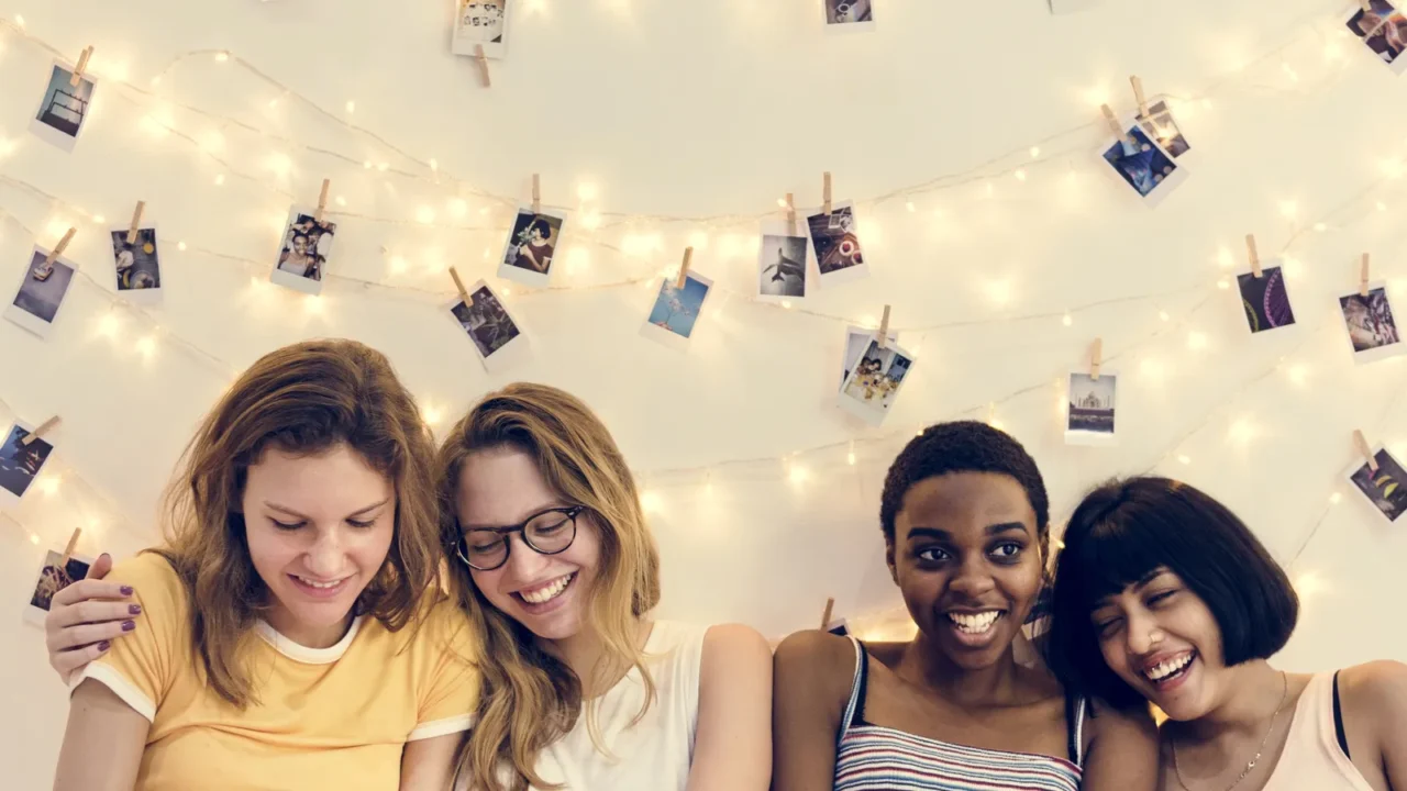 room with photo pictures on wall smiling girls sitting on