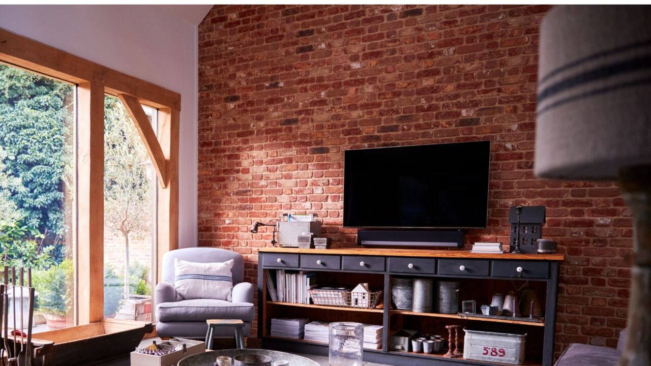 Interior of lounge with TV and exposed brick walls in modern open plan house or apartment.